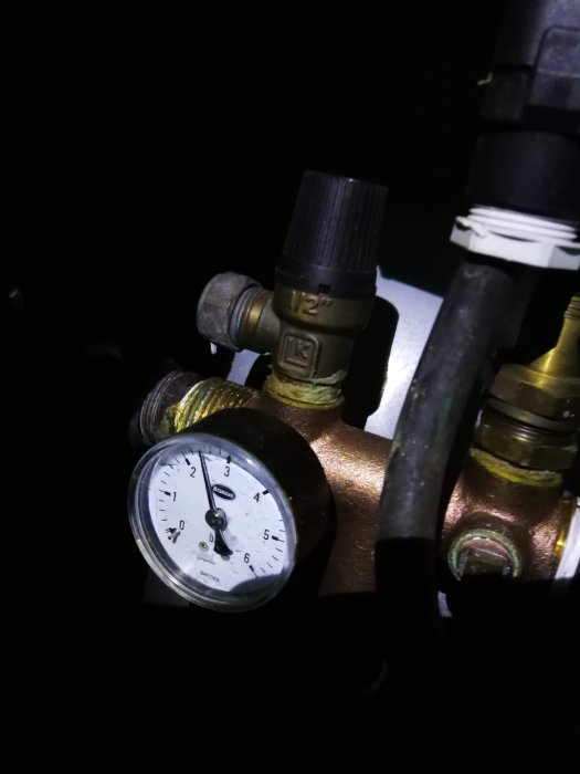 Manometer visar vattentryck i ett mörkt område, indikerar inget tryckfall när pumpen är på.