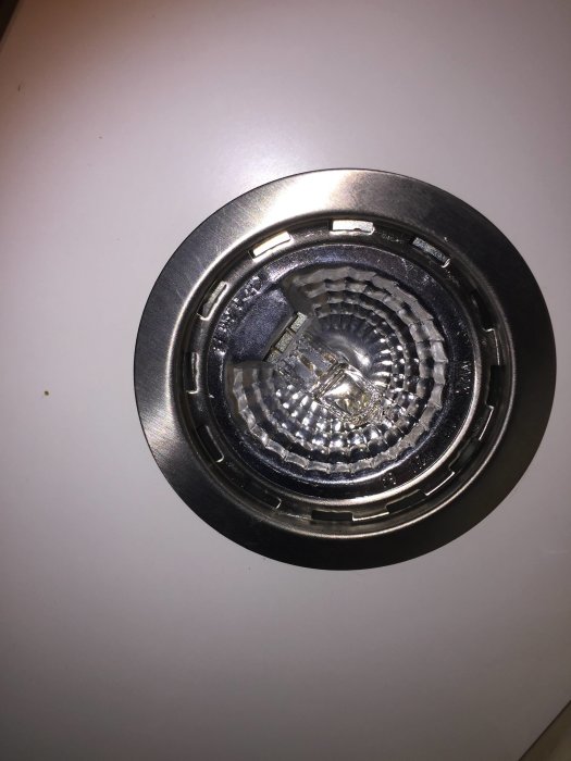 Spottarmatur utan glas, synlig reflektor och lös innerkant, installerad i tak.