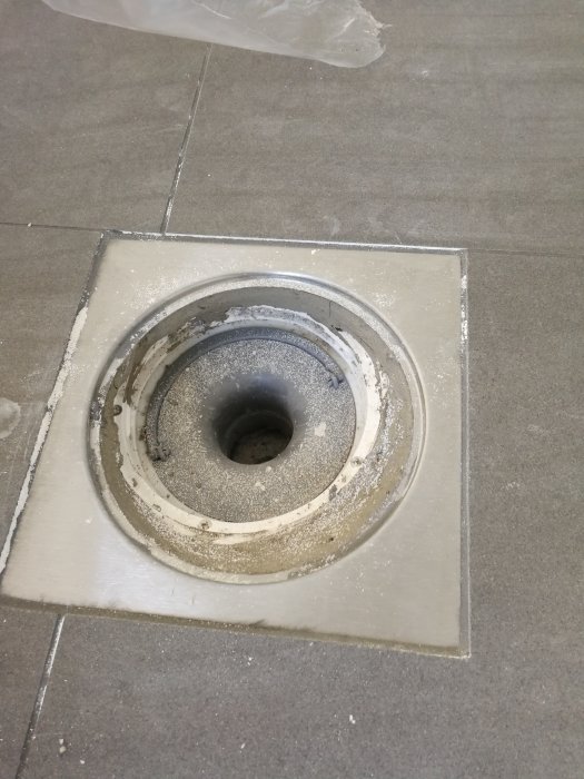 Golvbrunn under konstruktion med synligt murbruk och plast i brunnen, klinkerram ovanpå.