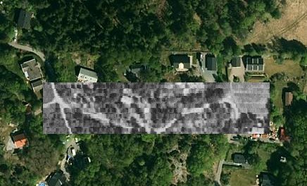 Luftbild med överlagrad gammal grundplan där hus expanderat bakåt, röd pixel markerar brunnen.