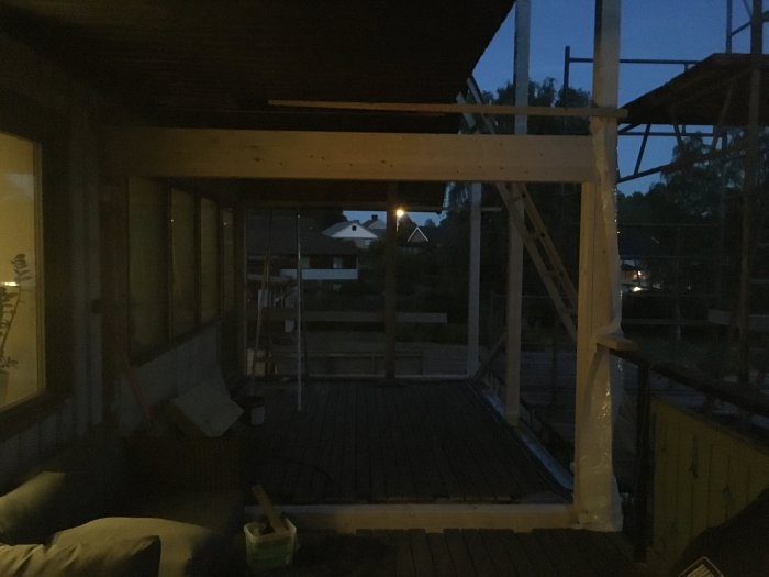 Halvfärdig träaltan under konstruktion i skymning med byggmaterial och verktyg.