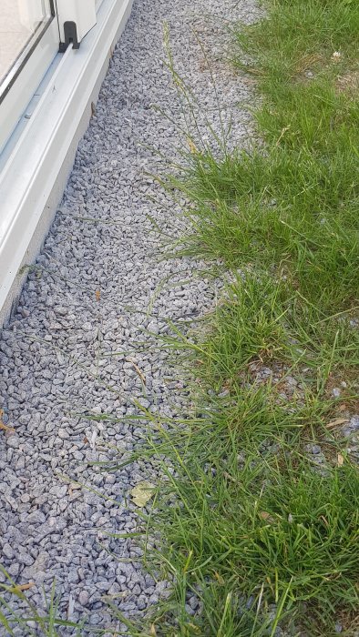Nybyggd altan med småsten längs kanten och övergång till gräs.