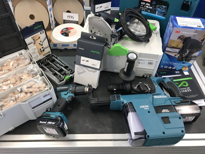 Verktyg och byggmaterial inklusive Festool Domino, hyvel och Makita borr på arbetsbänk.