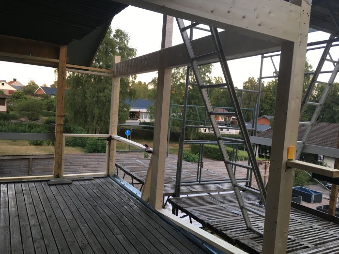 Byggplats med trästomme och stålbalk där limträbalk passar perfekt in, synlig del av ett byggtak.