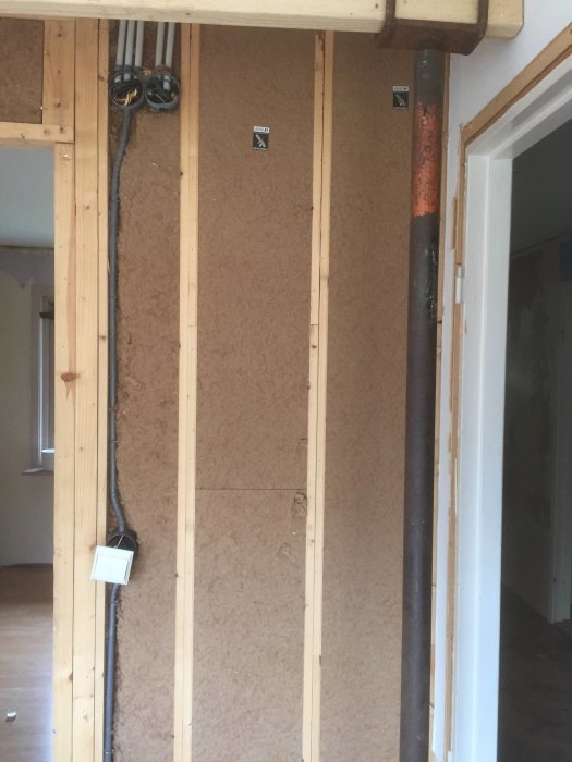 Renoveringsfas i hus med blottade elinstallationer och trästomme, innervägg åtgärdas.