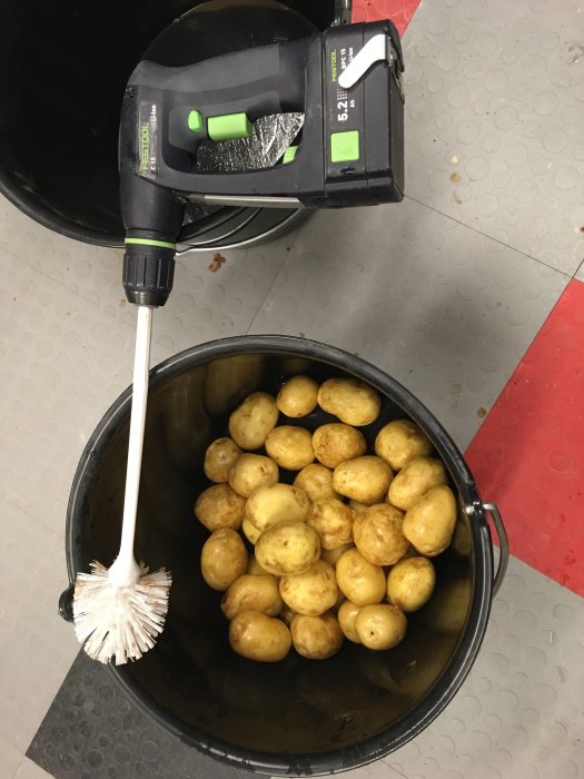 Borrmaskin med borste används för att rengöra potatis i en hink.