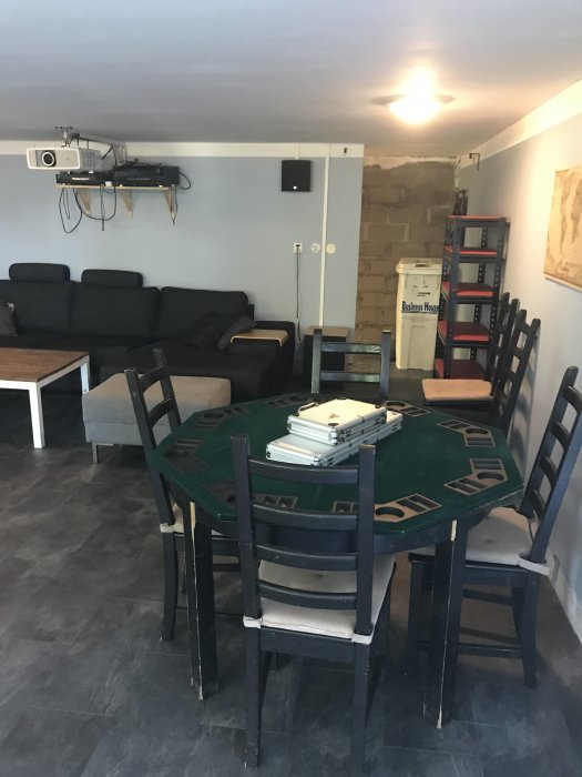 Ett renoverat vardagsrum klart för fotbollsmatch med pokerbord, soffa och projektor.