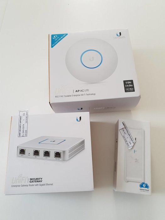 Ubiquiti-nätverksprodukter på ett bord: AP AC Lite, Security Gateway och Hybrid Cloud.