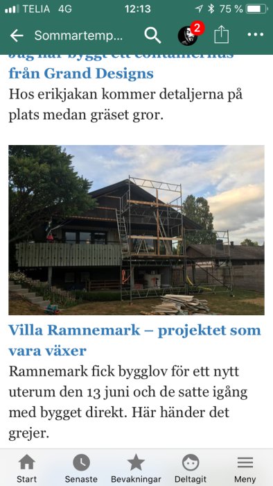 Byggnadsställningar runt en pågående tillbyggnad av ett tvåvåningshus med träbeklädnad i skymning.