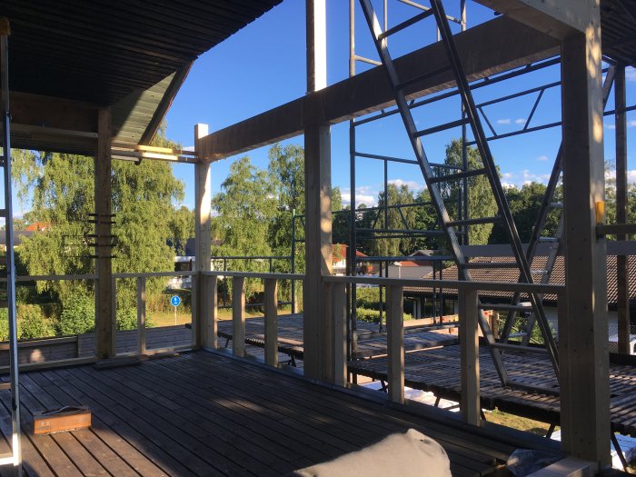 Renoverad bröstning på en träveranda med stålstomme och utsikt över en trädgård.