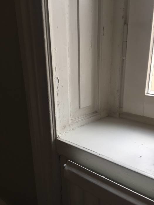 Fönsternisch med lös färg och sprickor som behöver punktspackling och ommålning.