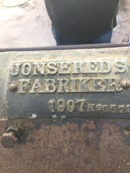 Närbild på en gammal rostig skylt med texten "Jonsereds Fabriker, 1907, No. 6571".