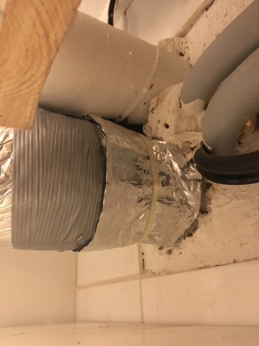 Kanalfläkt i källare kopplad till luft/luft-maskin med silvertejp och isolering.