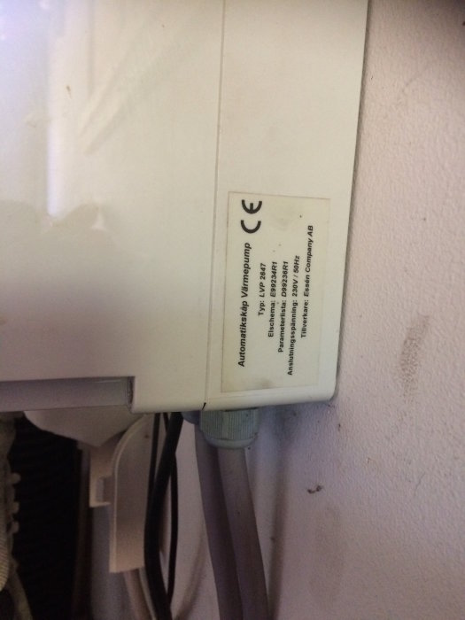Automatisk styrmodul för vatten/luft värmepump monterad på vägg med synliga elektriska kablar.