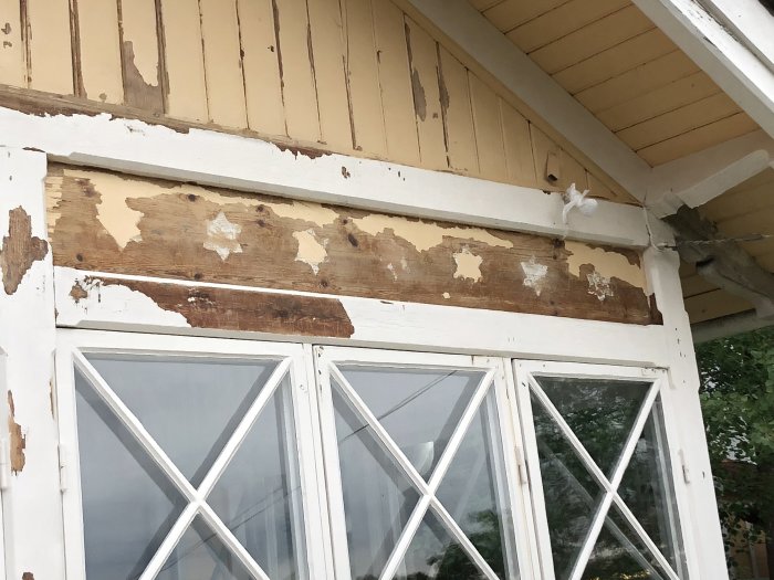 Delvis skrapad färg på ett trähus avslöjar underliggande målade vita stjärnor på fasaden.