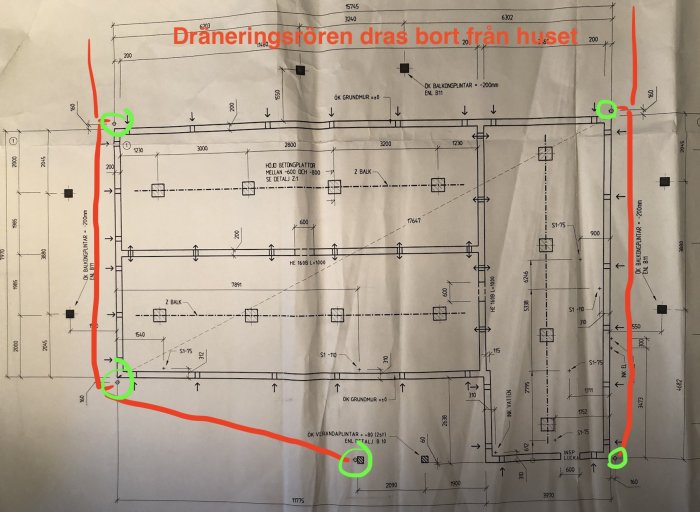 Ritning av husgrund med markerade dräneringsrör dragna bort från huset, handskrivna anmärkningar inkluderade.