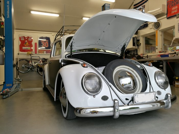 Volkswagen Typ 1 från 1964 med öppen framlucka i ett garage redo för regbesiktning.