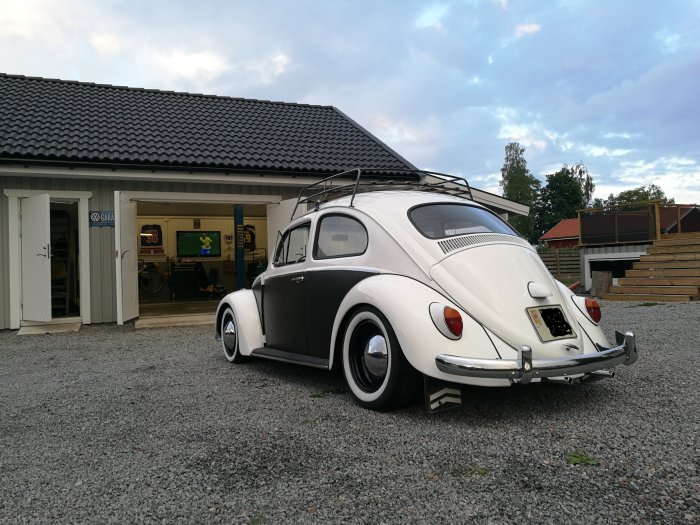 Restaurerad vit Volkswagen Typ 1 från 1964 parkerad utanför ett garage.