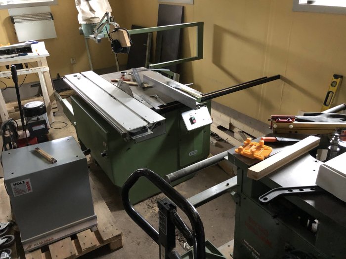 EJCA L1500 Profi sågning och fräsning maskin i ett verkstadssammanhang med diverse träbearbetningsutrustning.