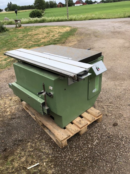 Grön EJCA L1500 Profi såg på en pall med landskap i bakgrunden.