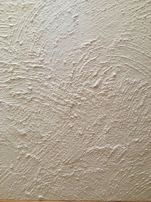 Vägg målad med borstad kalkfärg i naturlig beige nyans, strukturerad yta.