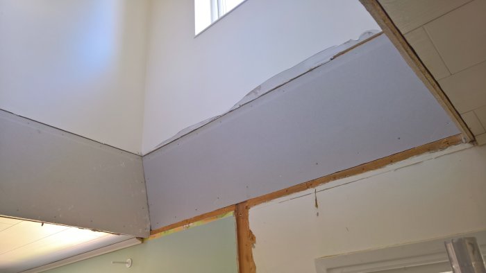 Nyklädd trapphålskant med gips och synliga träreglar i en under konstruktion hall.