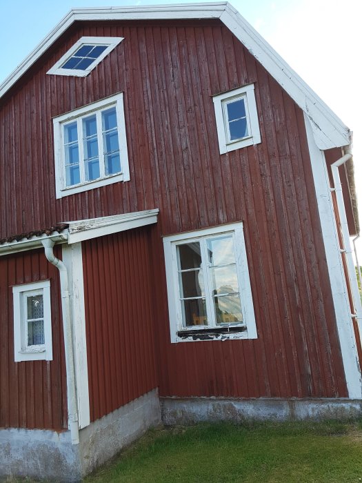 Rödfärgat hus med ett fönster utan karm i förberedelse för rivning.