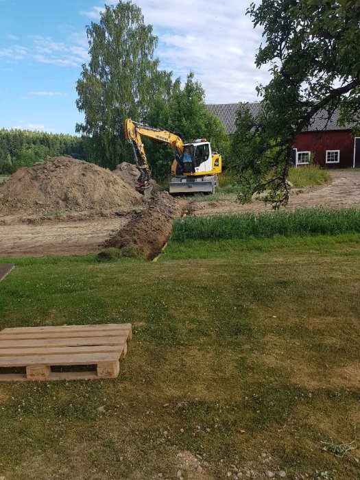 Grävmaskin gräver ny väg i grönt landskap, stora jordhögar syns vid sidan.