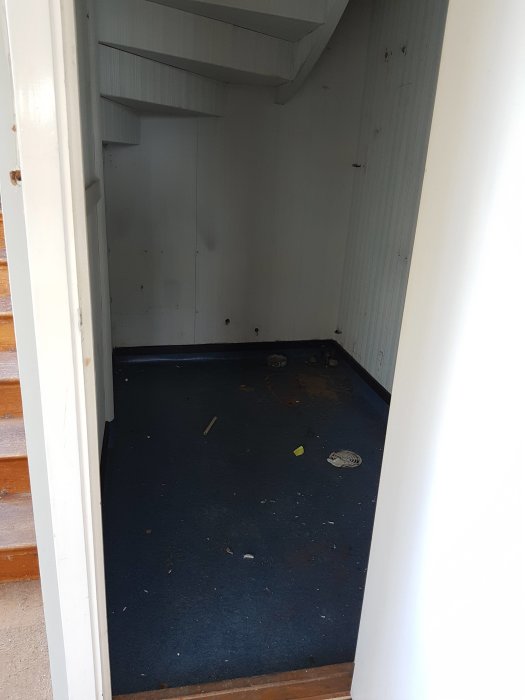 Gammal sliten golvmatta i ett tomt rum under en renovering.