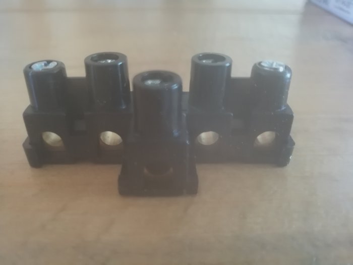 Svart kopplingsdosa med fem separata ledningsingångar på en träyta.