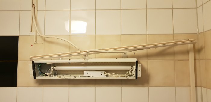 Elektrisk installation med öppet lysrörsskåp och synliga kablar på badrumsvägg.