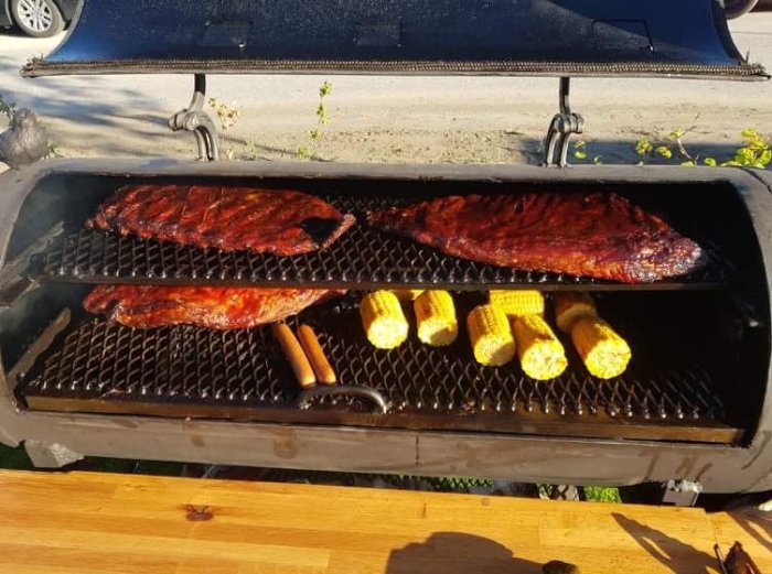 Grillad ribs och burnt ends med majskolvar på en öppen grill.