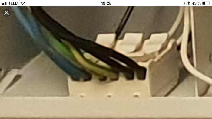 Närbild på elinstallation med blå, svarta och gulgröna kablar och deras anslutningar.
