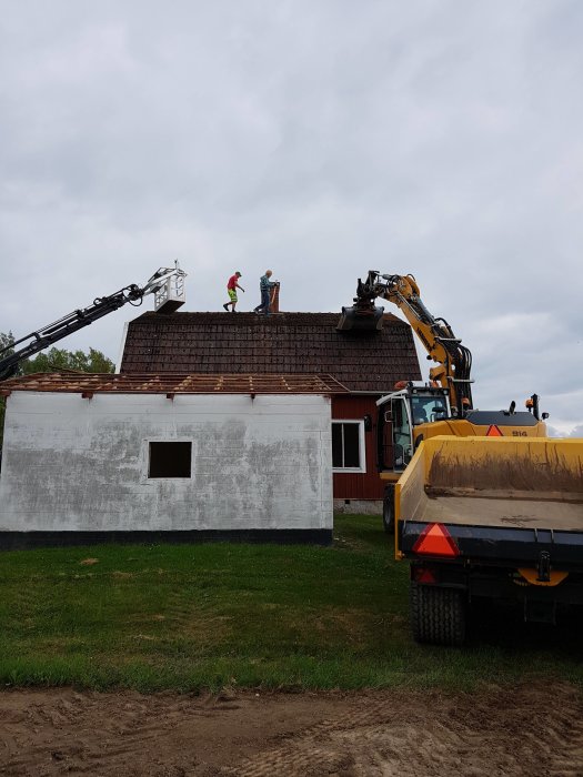Renovering av tak med arbetare och tunga maskiner som en grävmaskin och en lastbil.