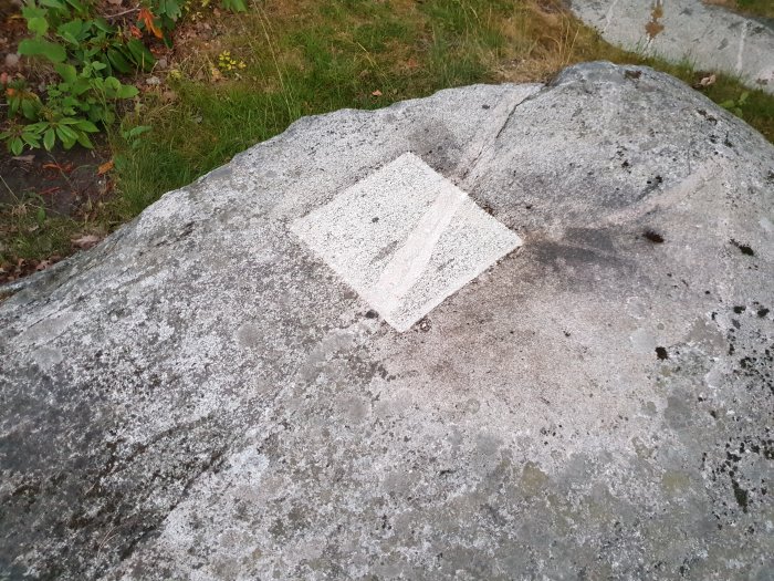 Blekt fyrkantig fläck på en berghäll där ett solur tidigare varit fastgjutet.