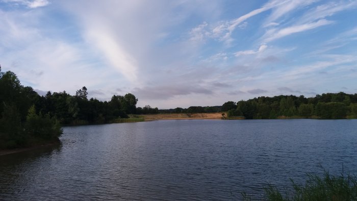 Tidig morgon vid en stilla sjö med moln på himlen och ingen soluppgång synlig.