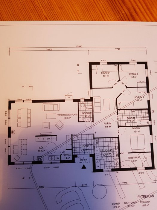 Arkitektritning av en våningsplanslösning med markerade sovrum, kök, vardagsrum, och andra utrymmen i ett hem.