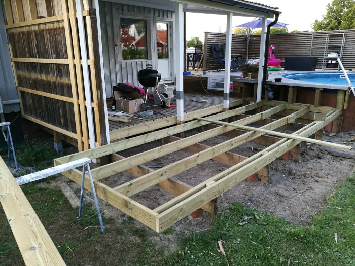 Renovering av altan med träbjälkar och pågående konstruktion under ett tak vid ett bostadshus.