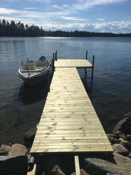 Nybyggd trall på en brygga med en båt förtöjd, i Hälsinglands skärgård.