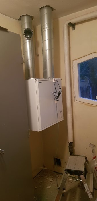 Installation av FTX-systemet Swegon Casa R5 pågår, med synliga ventilationsrör som går upp genom taket, och verktyg på golvet.