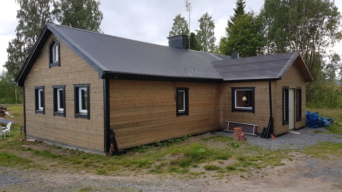 Ett hus med vitriolbehandlad träpanel och svart tak, panelen är 34x145 dubbelfasad och hyvlad.