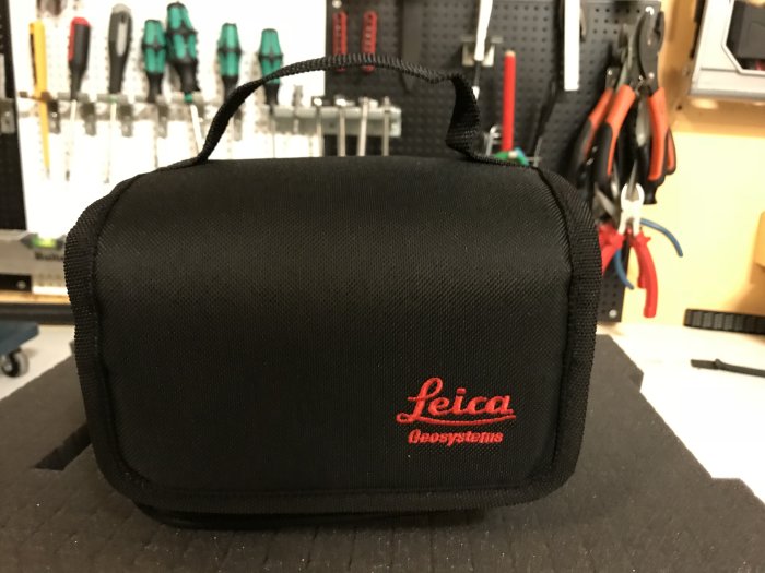 Svart Leica man-purse framför en verktygstavla med olika tänger.