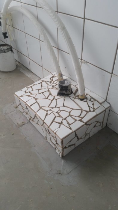 DIY-projekt av en klack täckt med hemgjord mosaik av krossade vit kakelplattor.