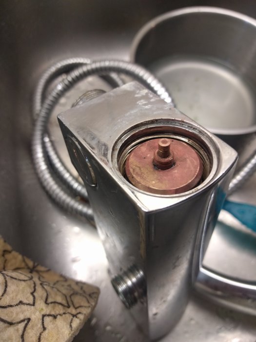 Demonterat överstycke på blandare med synlig känselkropp fast i mekanismen, i en diskho.