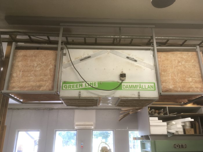 Monterad dammavskiljare "GREEN LINE DAMMFÅLLAN" i ett verkstadsutrymme.