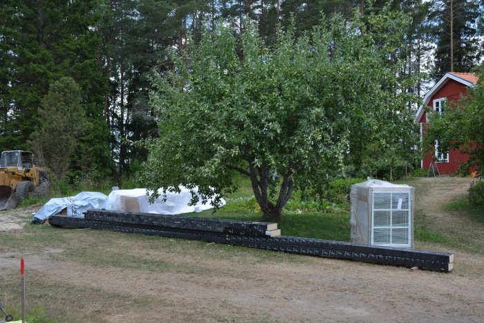 Formar för gjutning av plintar på en byggplats med material och en grävmaskin i bakgrunden.