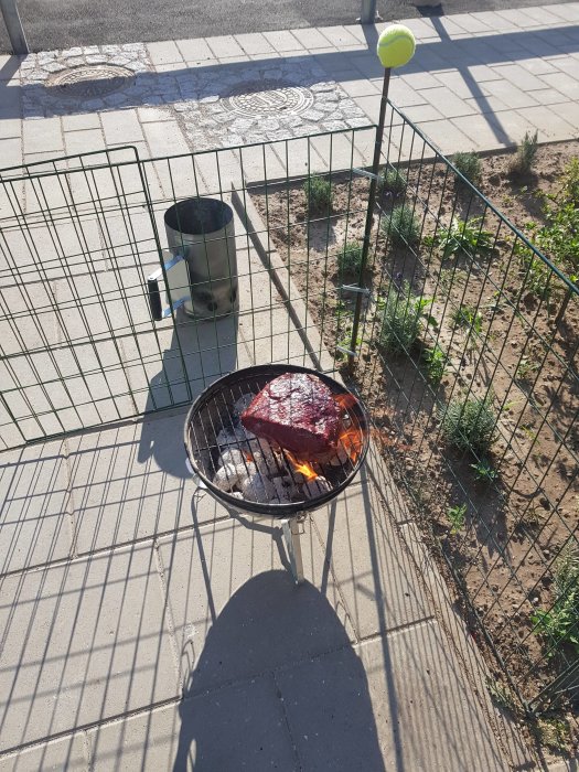 Picanha på liten kolgrill utomhus med skuggor på betong mark.