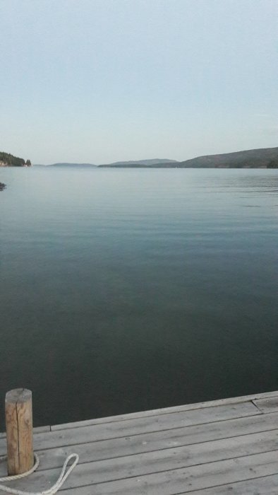 Vy över en sjö från en brygga vid skymning med Sveriges högsta ö i bakgrunden.