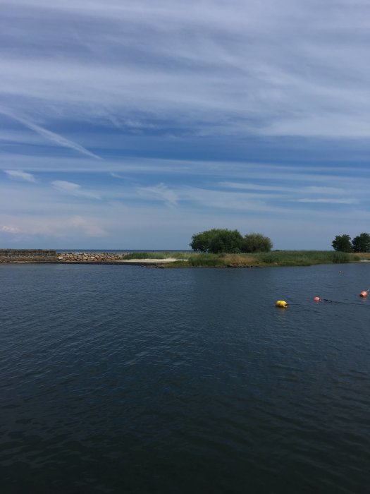 Vy över Kivik hamn med stilla vatten, små öar och en klar himmel.