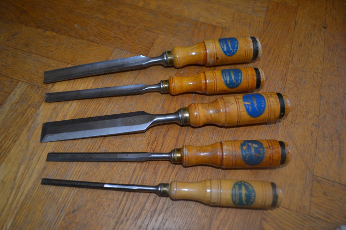 Fyra gamla E.A Berg stämjärn med blå etiketter och trähandtag på trägolv.